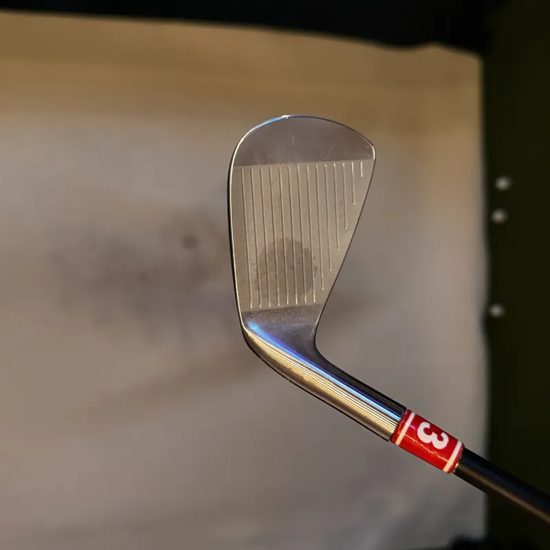 Seven-iron with a red numbered tag, the face angled toward the camera